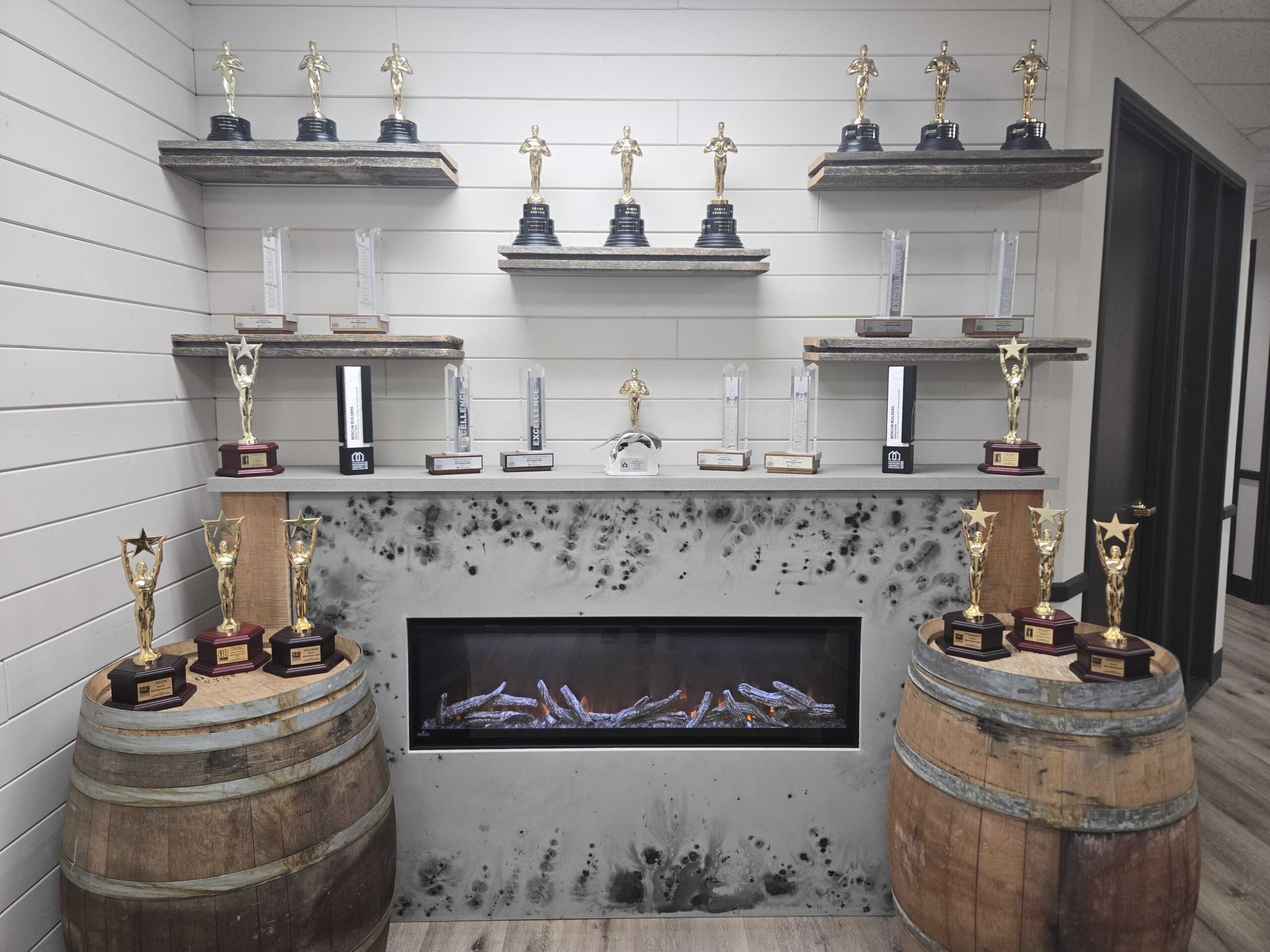 Bercum Builders award trophies from the Canadian Home Builders' Association displayed on shelves above a fireplace